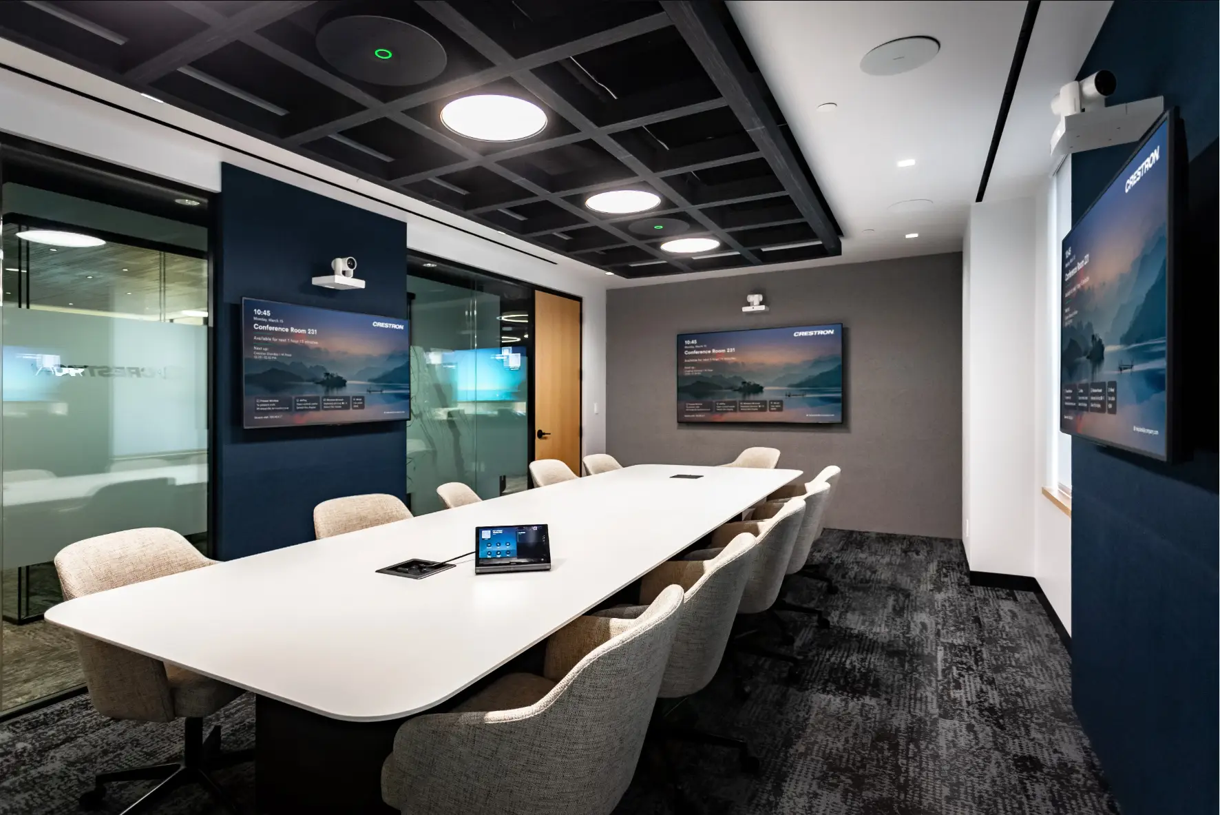 Modern meeting room with dual displays and a tabletop audiovisual controller.